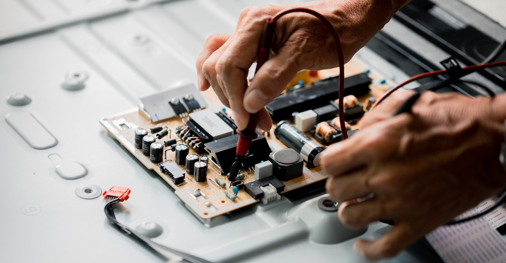 Technician in electronics lab measuring voltage electronic circuit board 